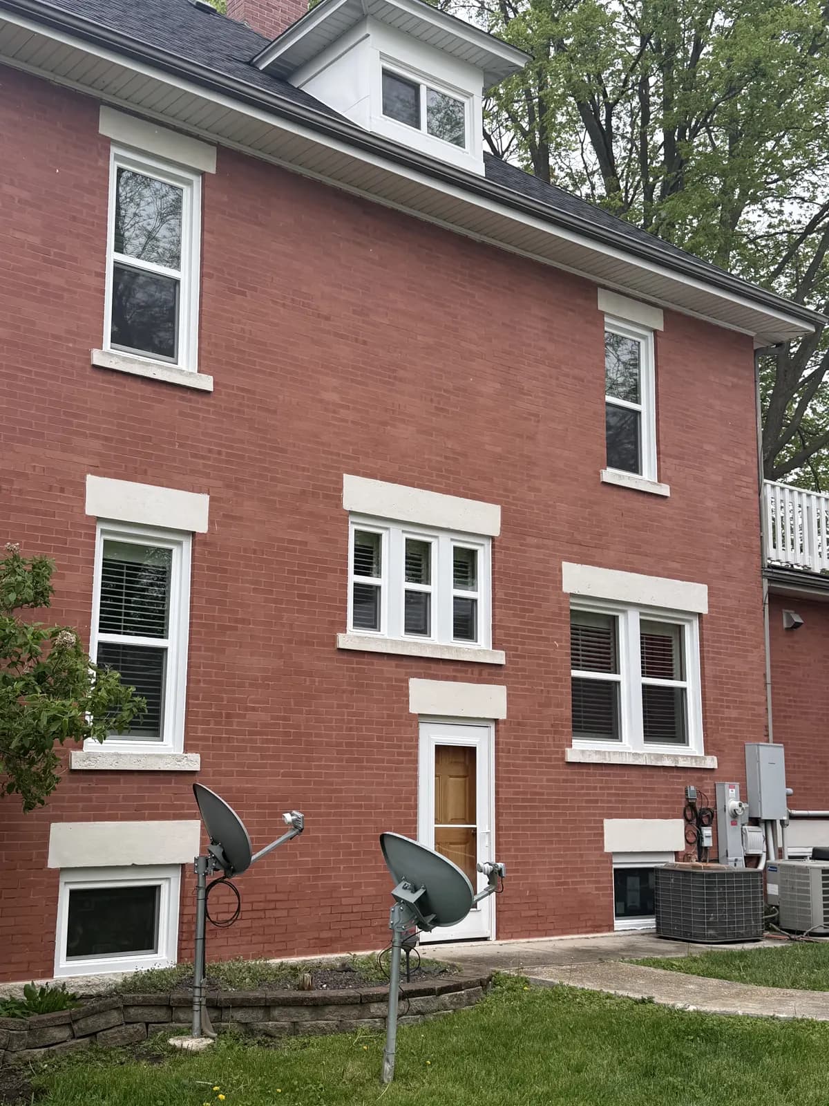 Red brick home with new white double-hung windows